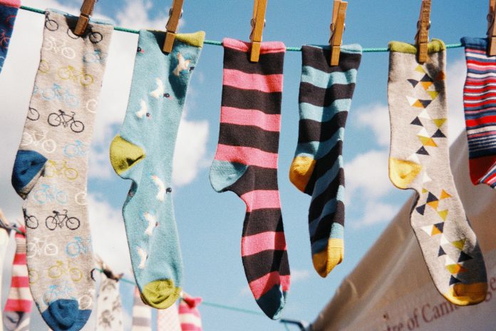 6 colorful socks hang on a clothing line.