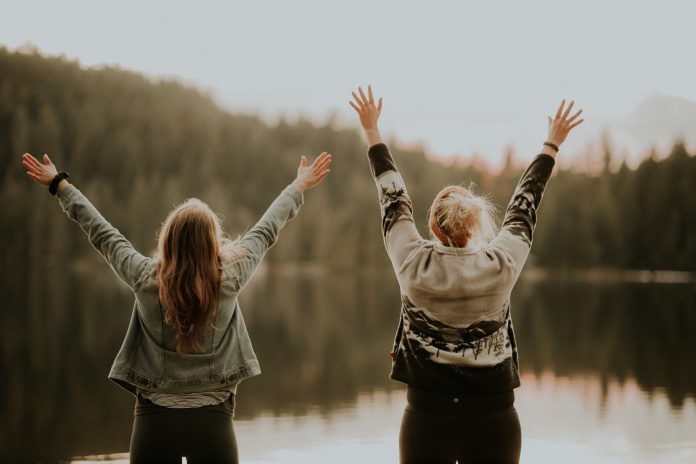 Two women with arms outstretched.