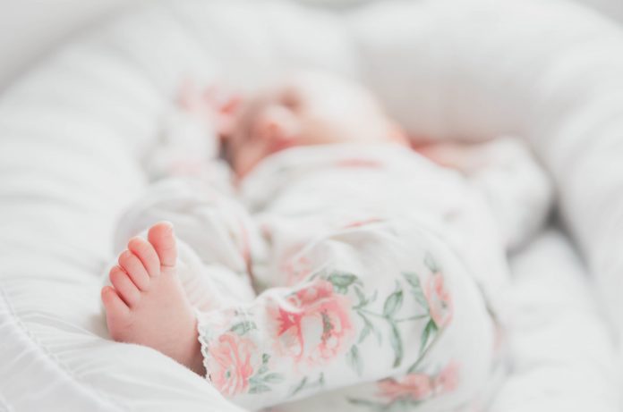 A blurred photo in which a newborn's foot is in focus.