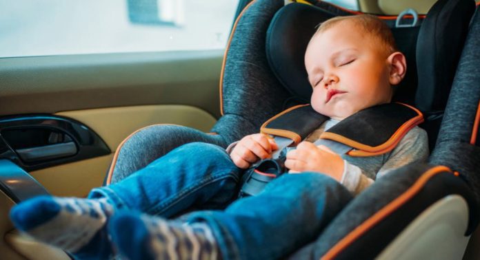 A toddler sleeps in a carseat.