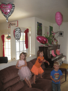 image of three young children on couch with heart balloons