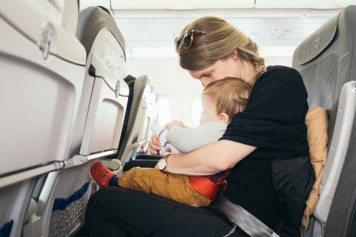 A woman with a child in her lap on an airplane.